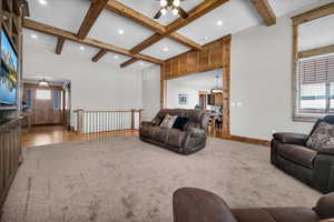 Carpeted living room featuring a ceiling fan, beamed ceiling, a chandelier, recessed lighting, and wood finished floors