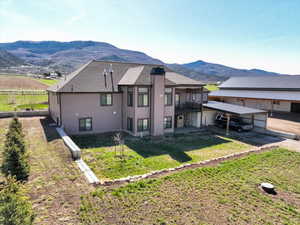 Rear view of property with a yard, fence, a mountain view, and driveway