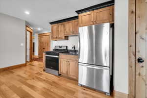 Kitchen with stainless steel appliances, light wood-style flooring, recessed lighting, and dark stone countertops
