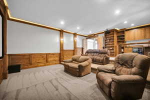Carpeted home theater room with a wainscoted wall, recessed lighting, and beverage cooler