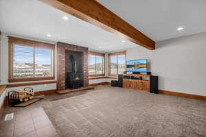 Unfurnished living room featuring a wood stove, recessed lighting, beam ceiling, and tile patterned flooring