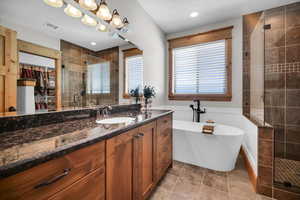 Full bathroom with a stall shower, vanity, a spacious closet, a soaking tub, and tile patterned floors