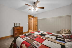 Bedroom featuring carpet flooring, a wainscoted wall, and a ceiling fan