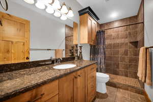 Full bathroom featuring vanity, a tile shower, and tile patterned flooring