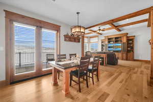 Dining room with light wood finished floors, beamed ceiling, a ceiling fan, a chandelier, and recessed lighting