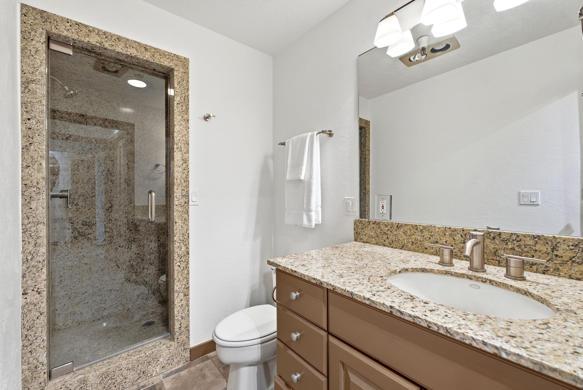 Full bathroom featuring vanity, a stall shower, and a chandelier
