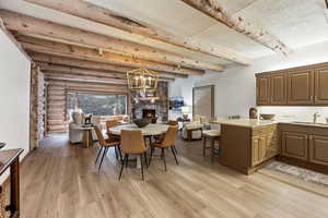Dining space featuring a fireplace, light wood-type flooring, beamed ceiling, and log walls
