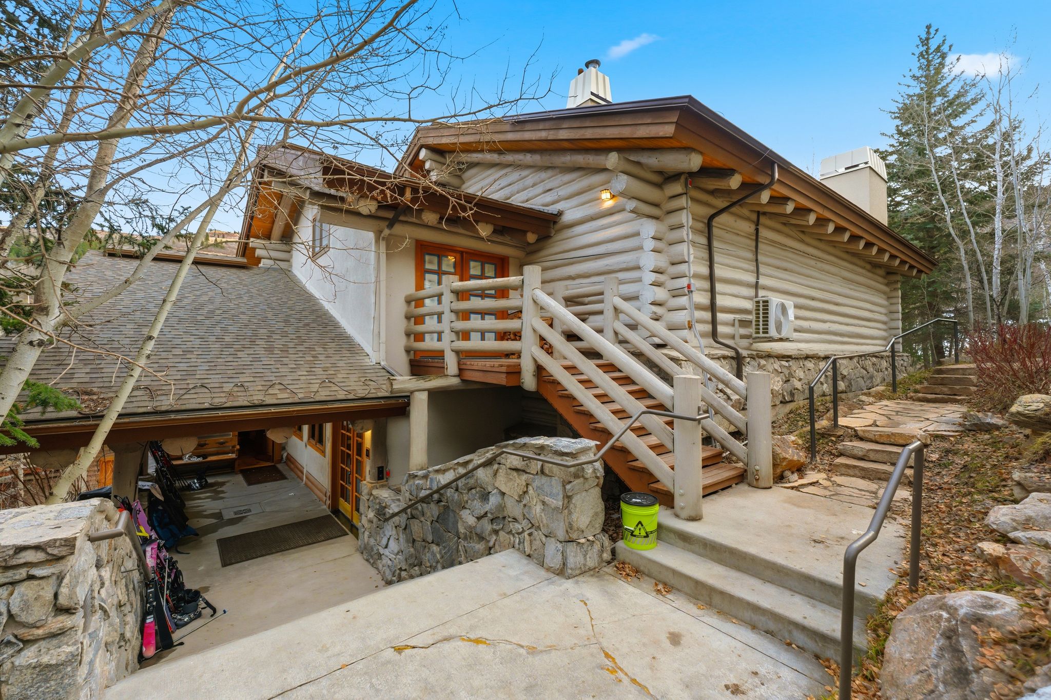 View of side of property with a chimney, stairway, log siding, and roof with shingles