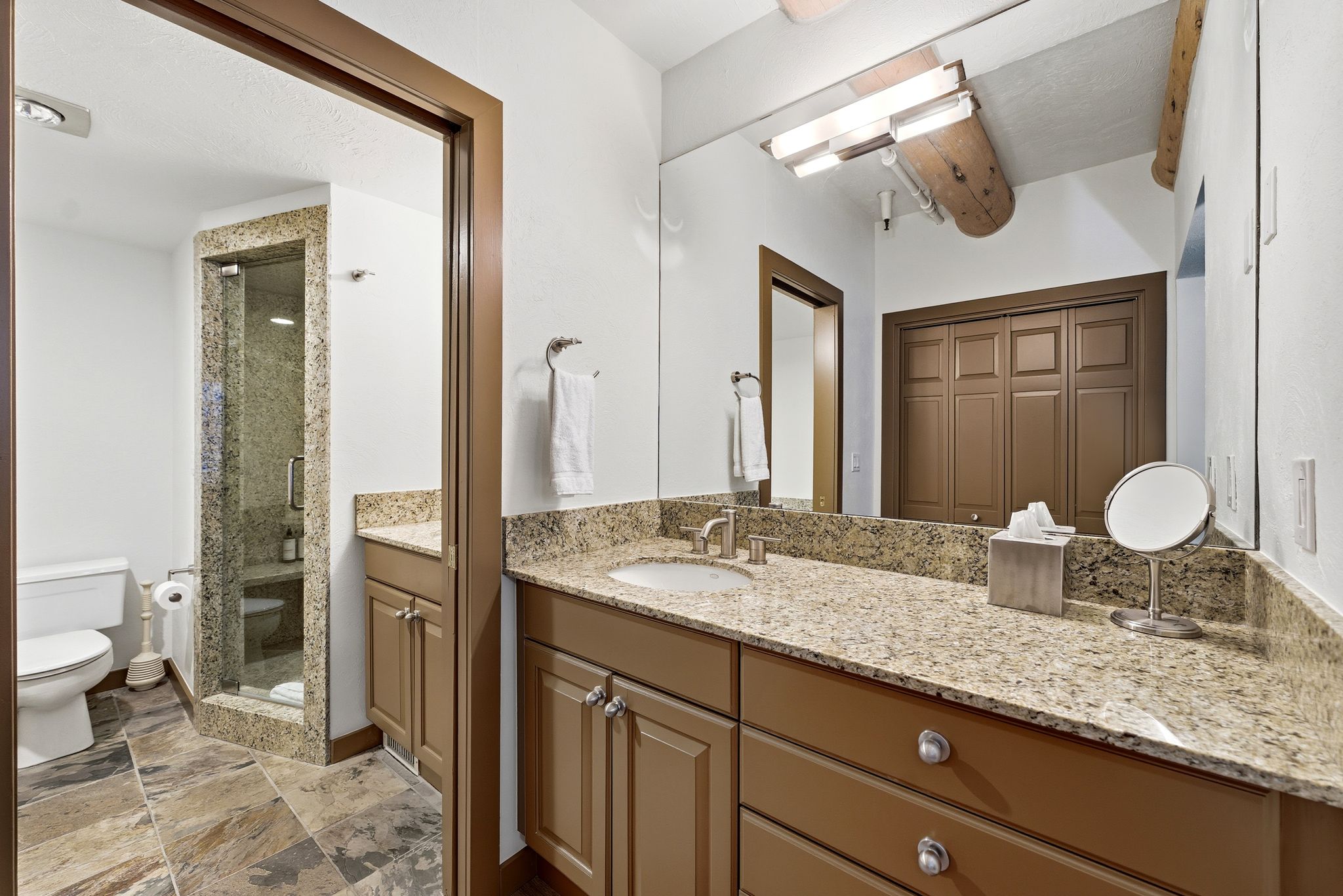 Full bathroom with vanity, a shower stall, a closet, and light stone finish flooring