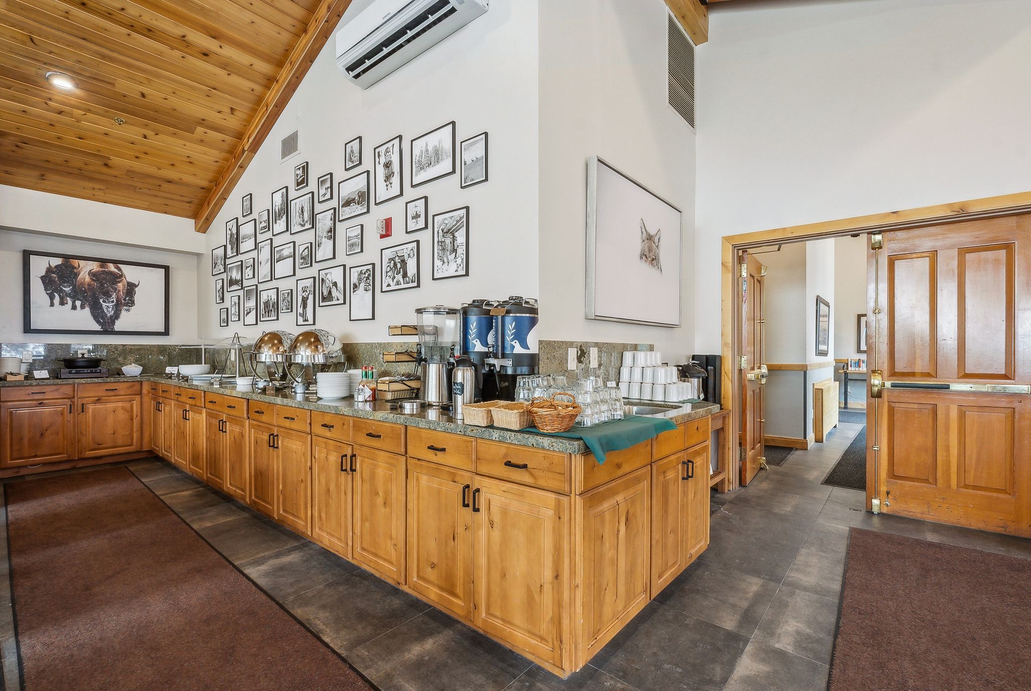 Kitchen with high vaulted ceiling, dark stone counters, wood ceiling, a wall mounted air conditioner, and brown cabinets