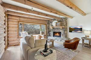 Living area with light wood-style floors, a fireplace, and beam ceiling