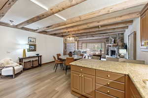 Kitchen featuring a fireplace, open floor plan, light stone countertops, hanging light fixtures, and a chandelier