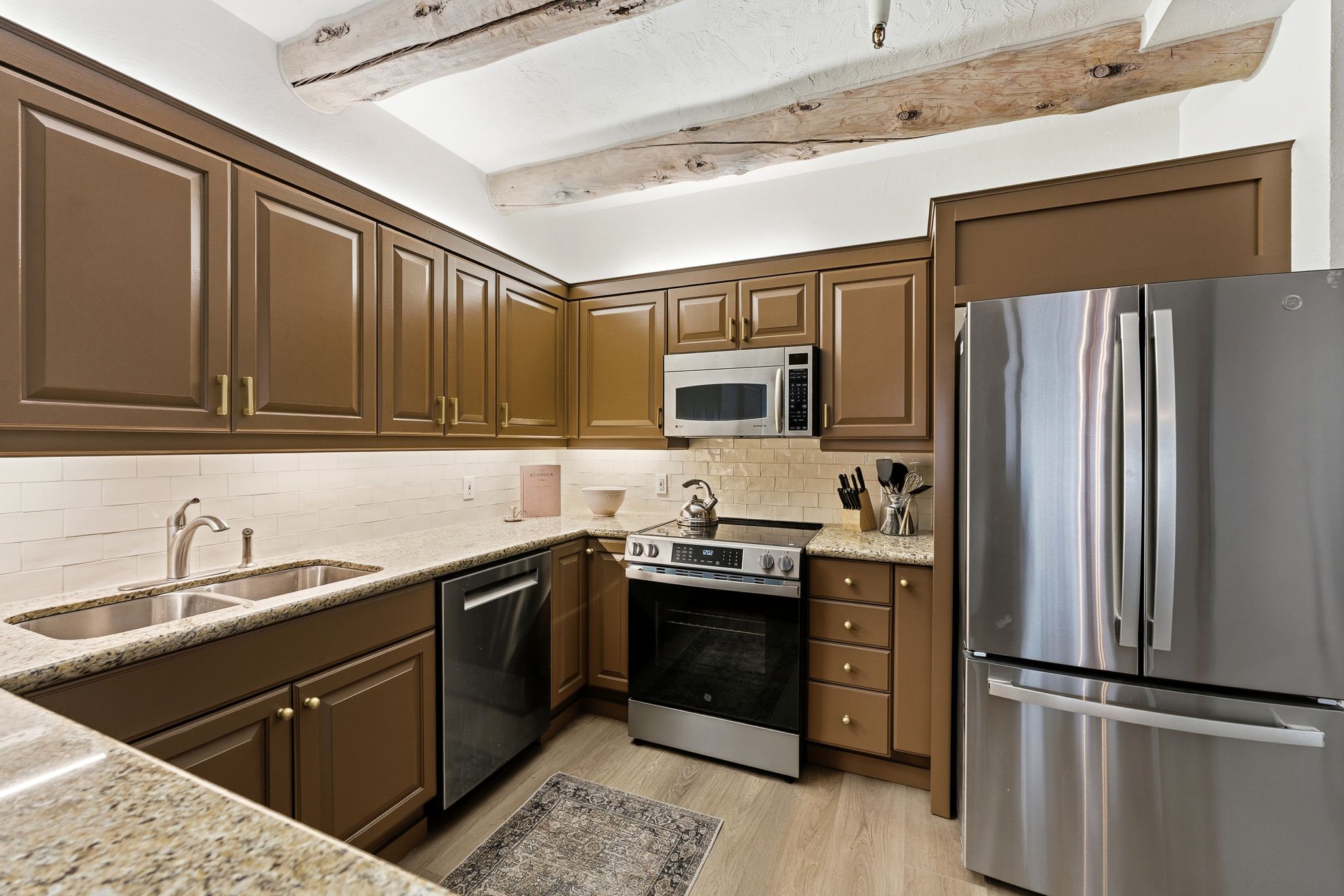 Kitchen featuring stainless steel appliances, light stone countertops, light wood-type flooring, and decorative backsplash