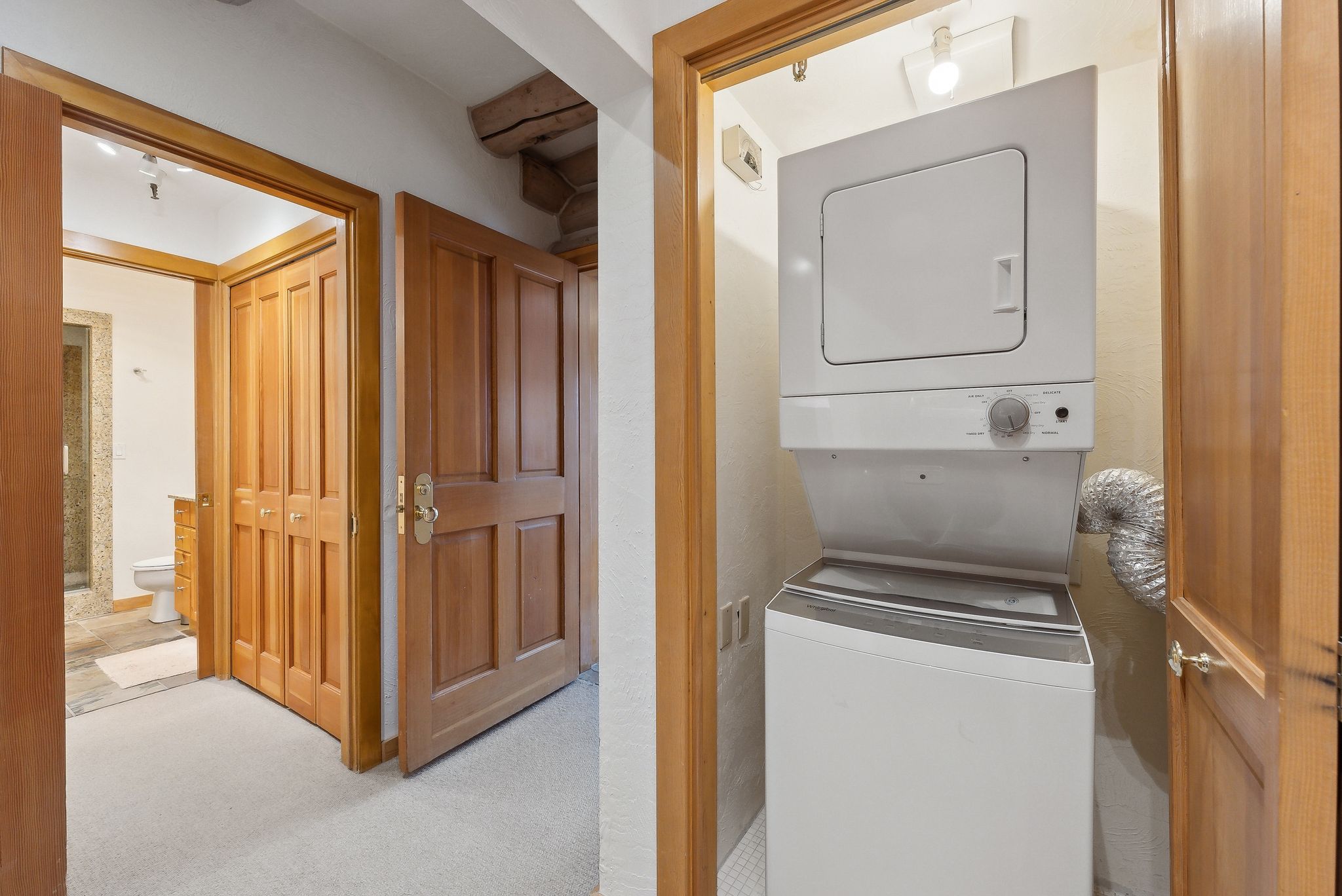 Washroom featuring stacked washer and clothes dryer and carpet