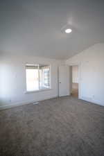 Unfurnished room with baseboards, carpet floors, visible vents, and vaulted ceiling