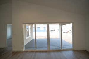 Unfurnished room with high vaulted ceiling, baseboards, and wood finished floors
