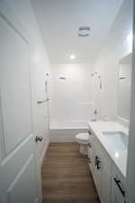 Bathroom featuring visible vents, toilet, wood finished floors, vanity, and  shower combination