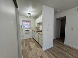 Kitchen with light wood-style flooring, white dishwasher, a wall mounted air conditioner, and a sink