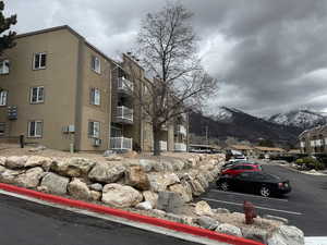 View of building exterior with a mountain view, cooling unit, and uncovered parking