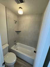 Bathroom featuring visible vents, toilet, bathtub / shower combination, and a textured ceiling