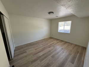 Empty room with visible vents, baseboards, a textured ceiling, and wood finished floors