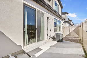 Entrance to property featuring stucco siding, a gate, central AC, fence, and a patio area