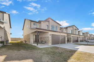 View of front of home with fence, an attached garage, stucco siding, concrete driveway, and stone siding