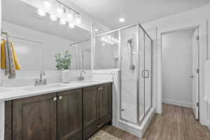 Full bath featuring a sink, a marble finish shower, and wood finished floors