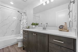 Bathroom with toilet, vanity, shower / tub combo, and wood finished floors