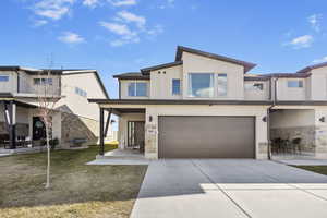 View of front of house featuring concrete driveway, a garage, stone siding, and stucco siding