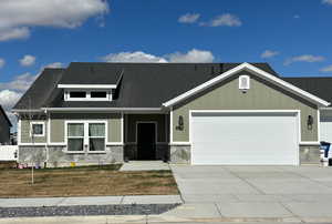 View of front of property featuring stone siding, board and batten siding, concrete driveway, and a garage