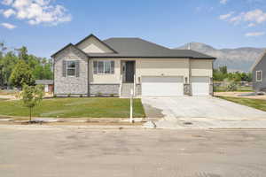 View of front of house featuring stone siding, stucco siding, a garage, and a front lawn