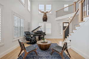 Sitting room with a towering ceiling, baseboards, wood finished floors, and stairs