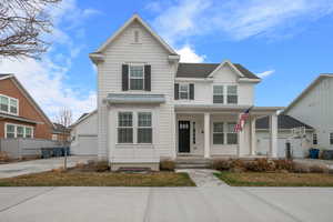 Traditional home featuring a garage, roof with shingles, a porch, and concrete driveway