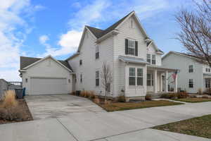 Traditional-style home with driveway, an attached garage, covered porch, central AC, and a shingled roof