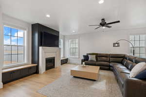 Living room featuring a fireplace, recessed lighting, light wood-style floors, and ceiling fan