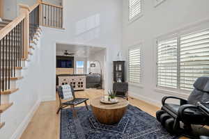 Living area with baseboards, plenty of natural light, wood finished floors, and stairs