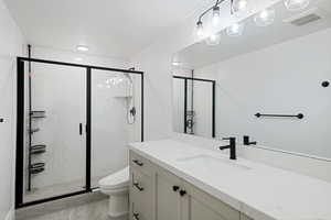 Bathroom with vanity, toilet, visible vents, and a stall shower