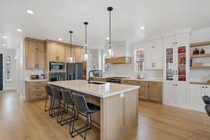 Kitchen featuring light wood finished floors, an island with sink, stainless steel appliances, a sink, and a kitchen breakfast bar