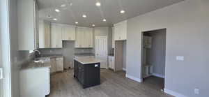 Kitchen featuring recessed lighting, light stone counters, light wood-style flooring, and a sink