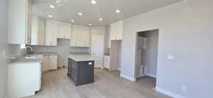 Kitchen with a sink, light stone counters, recessed lighting, light wood-style flooring, and baseboards