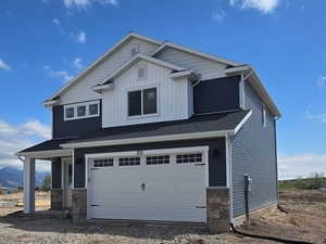 View of side of home with an attached garage, a mountain view, stone siding, and board and batten siding