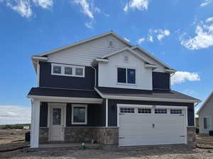 View of front facade with an attached garage, stone siding, and driveway