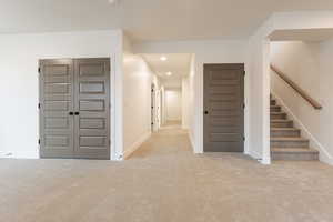 Hallway with carpet flooring, recessed lighting, stairs, and baseboards