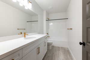 Full bath featuring washtub / shower combination, toilet, vanity, and wood finished floors