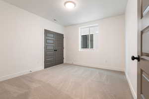 Unfurnished room featuring visible vents, baseboards, and light colored carpet