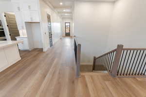 Hallway featuring recessed lighting, an upstairs landing, light wood-style floors, and baseboards