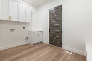 Washroom featuring baseboards, visible vents, light wood finished floors, cabinet space, and electric dryer hookup