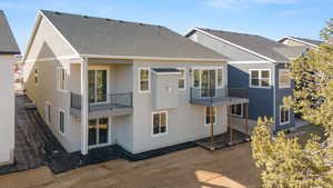 Back of property with a balcony, stucco siding, and roof with shingles