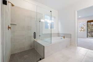 Full bathroom with tile patterned floors, baseboards, a stall shower, and a bath